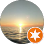 A setting sun over calm ocean waters, with gentle ripples reflecting the sunlight. An orange star icon is partially overlaid in the lower right corner of the circular image.