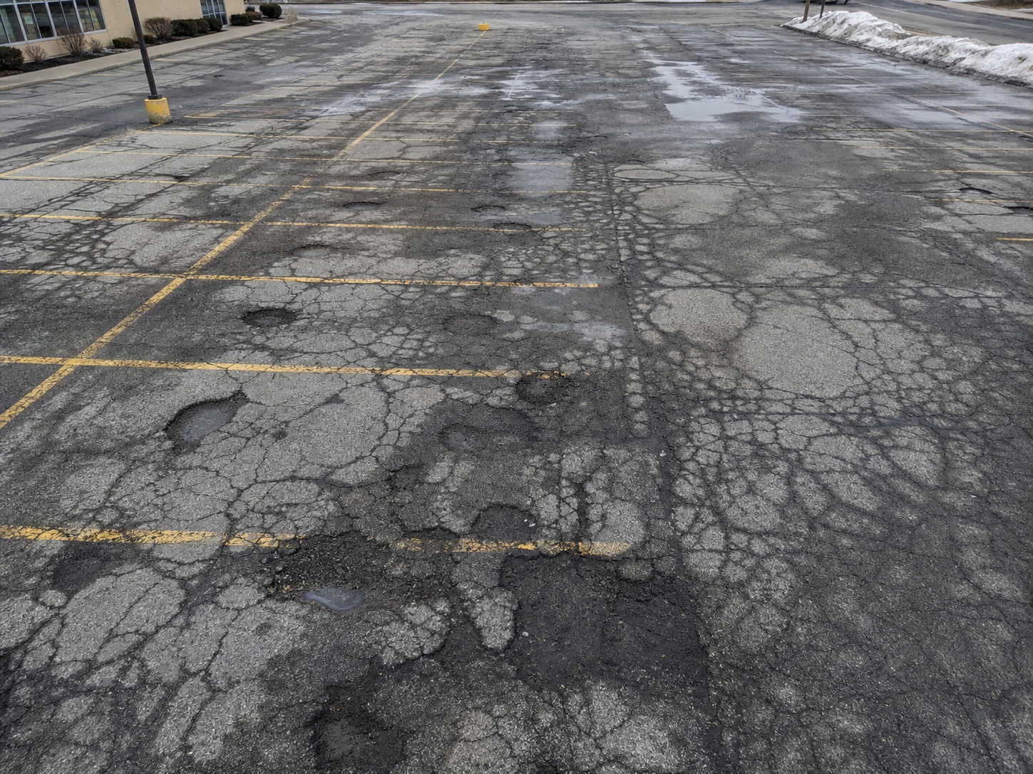 Cracked and potholed commercial parking lot in Cleveland Ohio showing winter freeze-thaw damage